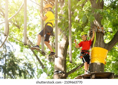 Child In Forest Adventure Park. Kids Climb On High Rope Trail. Agility And Climbing Outdoor Amusement Center For Children. Little Girl Playing Outdoors. School Yard Playground With Rope Way.