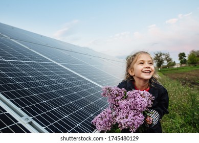 A child with a future of alternative energy and sustainable energy. The child holds flowers on a background of solar panels, photovoltaic. Environmental friendliness and clean energy concept. - Shutterstock ID 1745480129