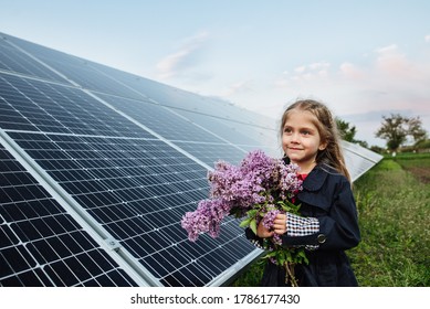 A child with a future of alternative energy and sustainable energy. The child holds flowers on a background of solar panels, photovoltaic. Environmental friendliness and clean energy concept. - Shutterstock ID 1786177430
