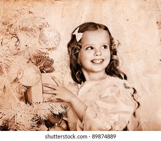 Child With Gift Box Near White Christmas Tree. Old Photo Toned Sepia.