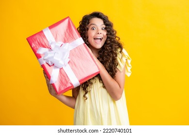 Child with gift present box on isolated studio background. Gifting for kids birthday. Excited teenager, glad amazed and overjoyed emotions.
