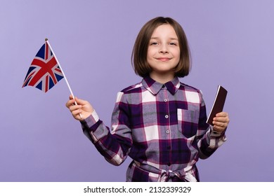 Child Girl 9-11 y.o. in plaid dress looking at camera. Schoolgirl holding passport and UK flag on lilac background, copy space, immigration..Study abroad concept.