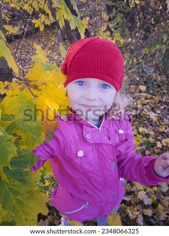 child girl in the autumn park with yellow leaves,Adorable preschooler girl enjoying nice and sunny autumn day outdoors