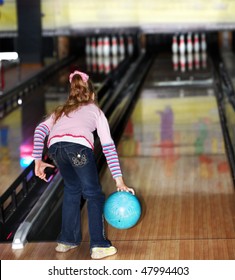 Child girl in with bowling ball learn game.