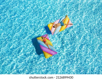 Child Girl And Boy On The Inflatable Mattress In The Crystal Clear Water By The Sea. Having Fun On Vacation At The Hotel Pool. Colorful Vacation Concept.