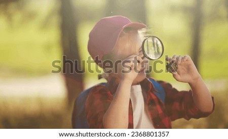 child girl boy scout studying pine cone in the forest with a magnifying glass. happy family child dream concept. child tourist explorer with magnifying glass in the forest lifestyle