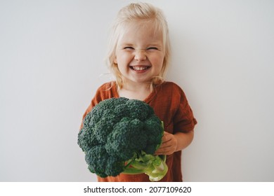 Child girl with broccoli healthy food vegan eating lifestyle organic vegetables plant based diet nutrition funny kid happy smiling 