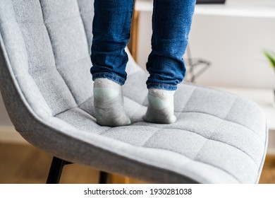 Child Girl Climbing Furniture. Accident Safety In Room