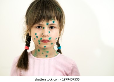 Child girl covered with green rashes on face ill with chickenpox, measles or rubella virus.