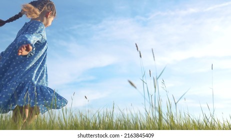 child girl dancing in the field park. happy childhood a family friendship concept. girl kid whirls in a blue dress in grass in the summer park. daughter in dancing whirls in the summer in nature sun