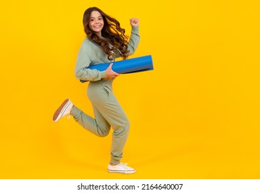 Child Girl Dressed In Sports Uniform. Child In A Posh Stylish Sports Suit In A Hoodie With A Hood Hold Yoga Mat. Run And Jump. Advertising Sportswear Tracksuit. Healthy Kids Lifestyle, Sport.