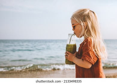 Child girl drinking smoothie vegan healthy lifestyle detox fruit beverage  breakfast organic raw nutrition summer vacations kid with juice bottle walking on beach