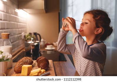 Child Girl Is Drinking Water In The Kitchen At Home
