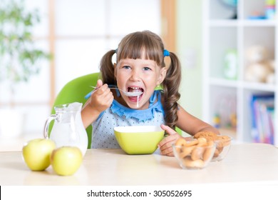 child girl eating healthy food at home in kitchen - Shutterstock ID 305052695