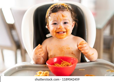 Child Girl, Eating Spaghetti For Lunch And Making A Mess At Home In Kitchen