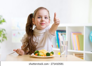 Child Girl Eats Healthy Food Showing Thumb Up At Kindergarten