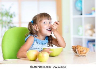 Child girl eats tasty breakfast in nursery