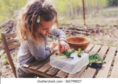 Child Girl Exploring Nature In Early Spring, Looking At First Sprouts With Loupe. Teaching Kids To Love Nature.