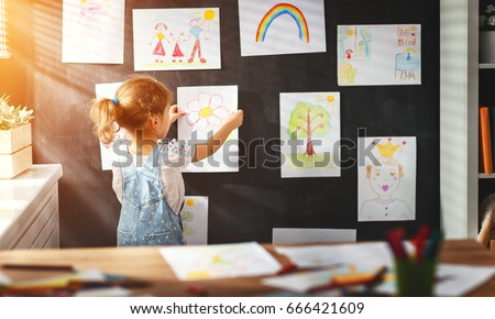 child girl hanging her drawings on the wall