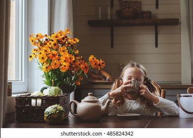 Child Girl Having Breakfast At Home In Autumn Morning. Real Life Cozy Modern Interior In Country House. Kid Eating Bagels And Drinking Tea. 