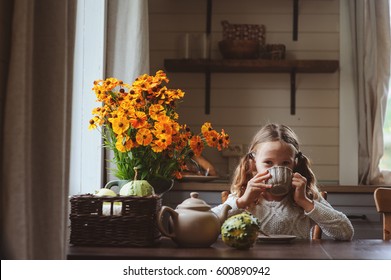 Child Girl Having Breakfast At Home In Autumn Morning. Real Life Cozy Modern Interior In Country House. Kid Eating Bagels And Drinking Tea. 