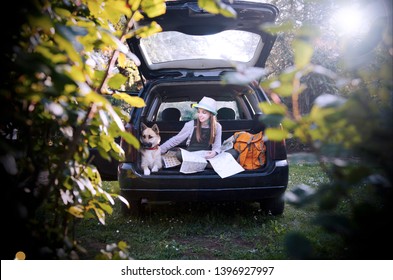 Child girl and her dog pet in car trunk having travel break to see the map.Parking place in nature for camping.Traveling on holiday by car - Powered by Shutterstock