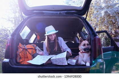 Child girl and her dog pet in car trunk having travel break to see the map.Parking place in nature for camping.Traveling on holiday by car - Powered by Shutterstock