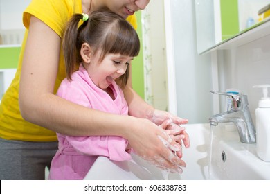 Child Girl And Her Mother Washing Hands With Soap In Bathroom