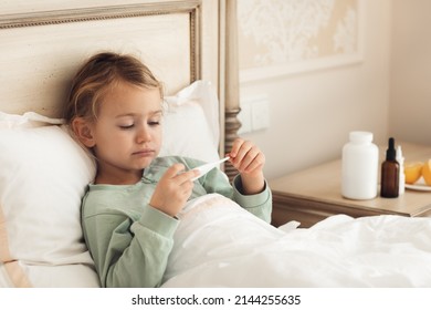 Child Girl Laying Down Bed At Home, Sick Day, Feeling Bad Measures Temperature Taking Medicine. Virus Cold Season Illness