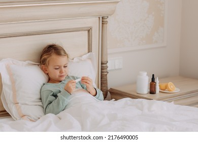 Child Girl Laying Down Bed At Home, Sick Day, Feeling Bad Measures Temperature Taking Medicine. Virus Cold Season Illness