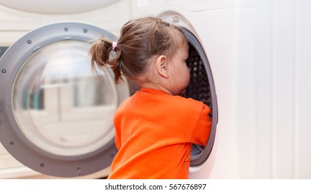 Child Girl Is Looking Into The Washing Machine