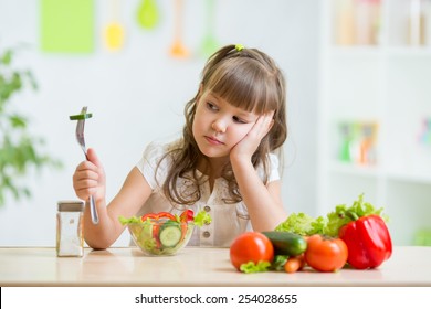 Child girl looks with disgust for healthy food