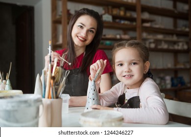 Child Girl With Mother At Pottery Workshop Painting Pottery
