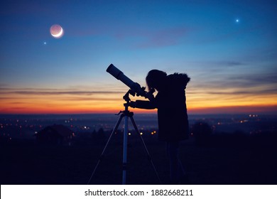 Child girl observing stars, planets, Moon and night sky with astronomical telescope. - Shutterstock ID 1882668211