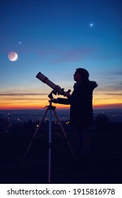 Child girl observing stars, planets, Moon and night sky with astronomical telescope.