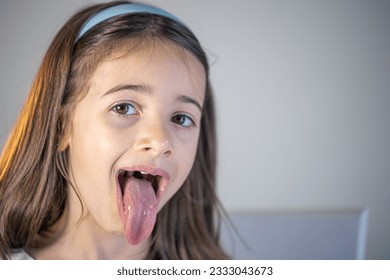 A child girl open her mouth and show her tounge. - Powered by Shutterstock