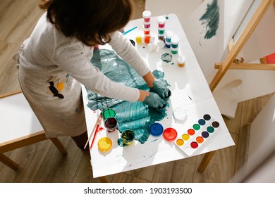 Child Girl Painting Her Hand With Paint And Paintbrush. Finger Painting Or Art Therapy For Children. Fun Activities For Toddlers.