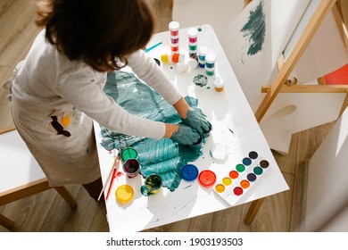 Child girl painting her hand with paint and paintbrush. Finger painting or art therapy for children. Fun activities for toddlers. - Powered by Shutterstock