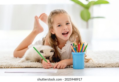 Child girl painting and ragdoll kittens the floor   smiling  Little female person drawing and colorful pencils   kitty pets close to her at home
