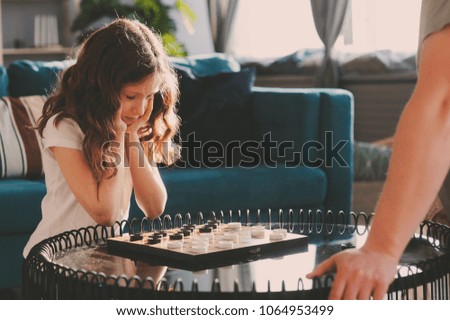 lifestyle shot of smart kid girl playing checkers at home