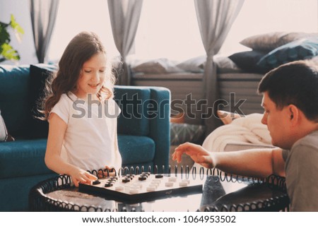 Similar – child girl playing checkers with her dad at home