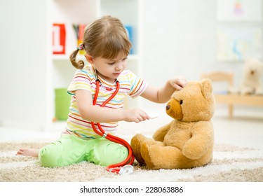 Child Girl Playing Doctor And Curing Plush Toy Indoors