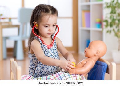 Child Girl Playing Doctor With Doll At Home