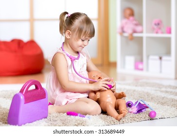 child girl playing doctor with toy at home