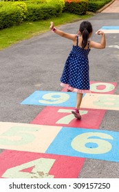 Child Girl Playing Hopscotch On Playground