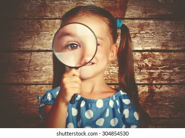 Child Girl Playing With A Magnifying Glass In The Detective