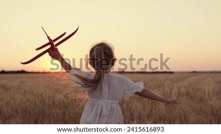 Child girl plays with toy airplane on field, kid fly into future. Kid aviator girl wants to become pilot astronaut. Slow motion. Child play with toy airplane. Teenager dreams of flying, becoming pilot