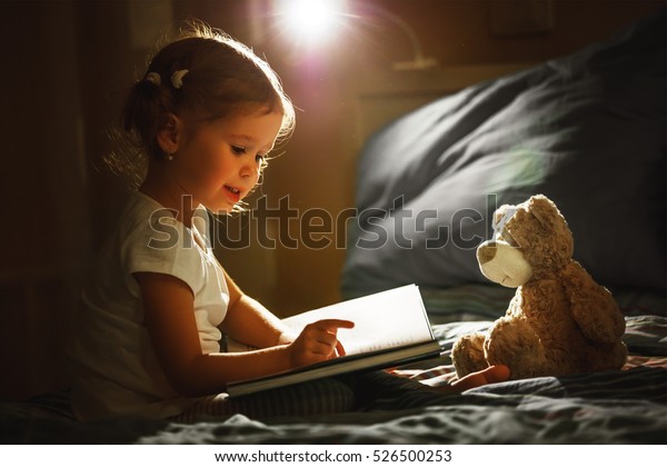 寝る前にベッドで本を読む少女 の写真素材 今すぐ編集