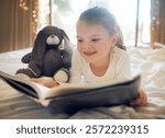 Child, girl and relax on bed with reading book for learning, fantasy story and language development. Kid, smile and teddy bear with novel for fairytale literature, storytelling and education at house