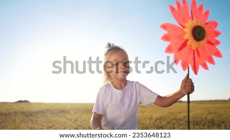 child girl running with windmill a toy lifestyle in the park. happy family kid dream concept. daughter girl playing with a toy windmill in nature. childhood freedom wind concept outdoors